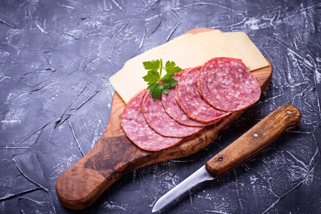 Rodajas de queso y salami sobre tabla de madera