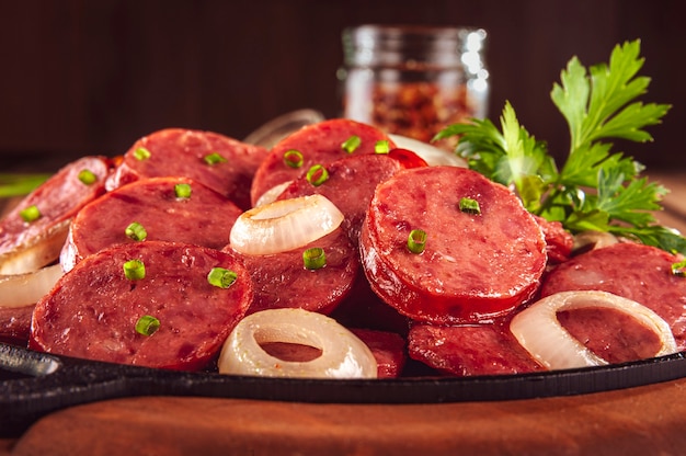 Rodajas de salchicha calabrese ahumada en un fondo de madera - primer plano de aperitivo brasileño