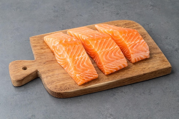 Rodajas de salmón crudo con placa de madera sobre fondo de piedra