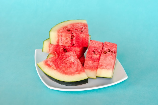 Rodajas de sandía en un plato sobre fondo azul. Postre de verano sabroso fresco jugoso. Foto de stock