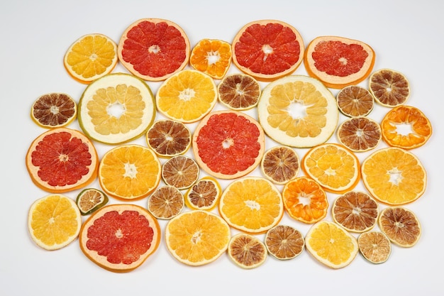 Rodajas secas de diversas frutas cítricas sobre fondo blanco.
