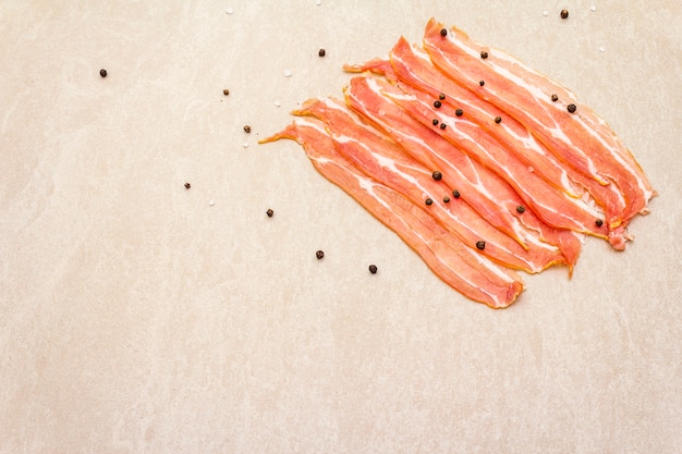 Rodajas de tocino ahumado con granos de pimienta