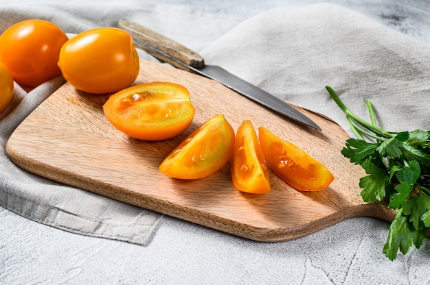 Rodajas de tomate cherry amarillo fresco en una tabla de cortar