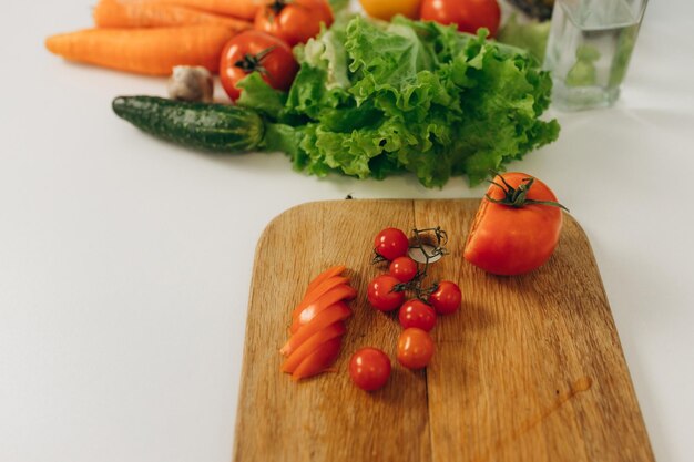 Rodajas de tomate en un tablero de cocina Muchas verduras en la mesa