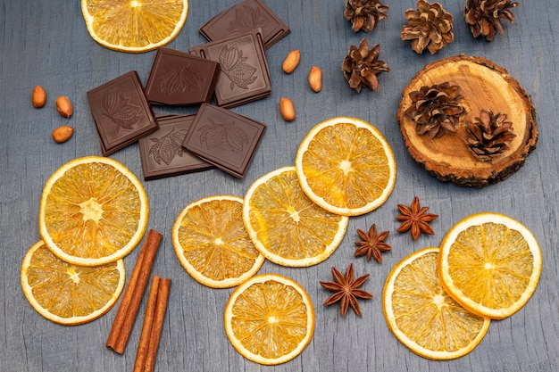 Rodajas de trozos de naranja seca de palitos de canela de chocolate y conos en un tocón