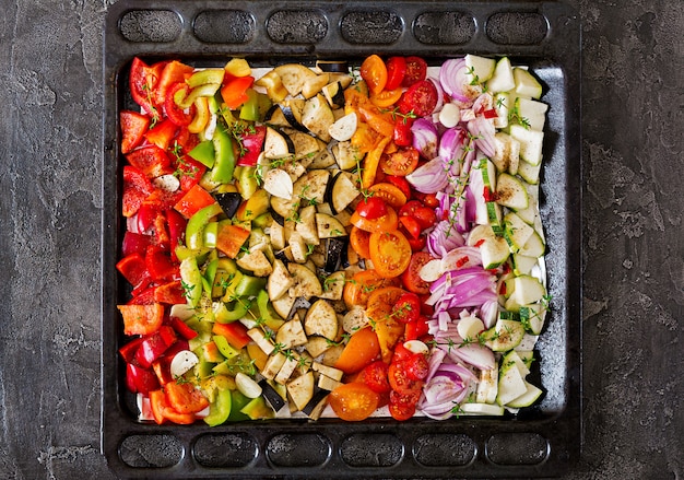 Rodajas de verduras en la bandeja para hornear preparada para hornear. Berenjenas, calabacines, tomates, pimentón y cebolla. Vista superior