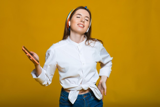 Rodilla figura de joven hermosa mujer caucásica escuchando música con auriculares bailando sonriendo