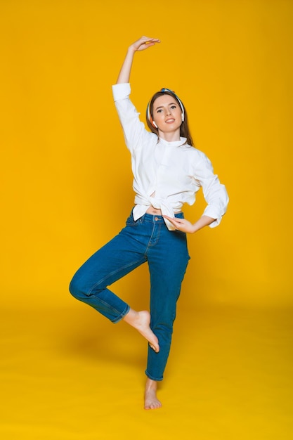 Rodilla figura de joven hermosa mujer caucásica escuchando música con auriculares bailando sonriendo