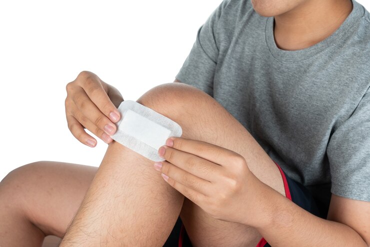 Foto rodilla de niño asiático con un vendaje adhesivo y hematoma. el muchacho asiático pone una venda adhesiva en la rodilla.