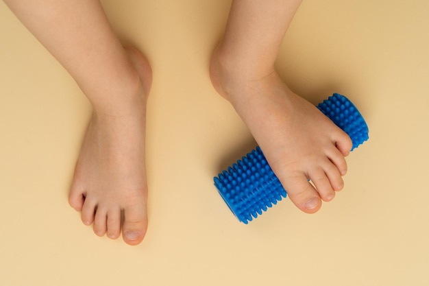 Rodillo de aguja azul para masajes y fisioterapia en un fondo beige con la imagen de un niño