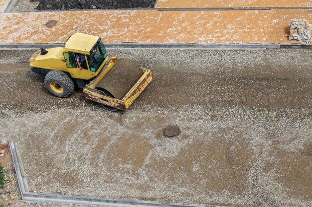Un rodillo compactador nivela y compacta la arena antes de colocar el asfalto en un sitio de construcción