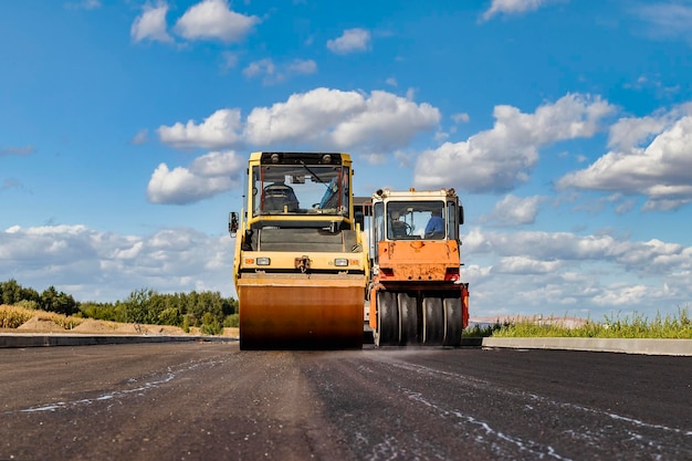 El rodillo compactador vibratorio coloca asfalto en una nueva carretera en construcción. Primer plano del trabajo de la maquinaria vial. Trabajos de construcción en la construcción de carreteras urbanas.