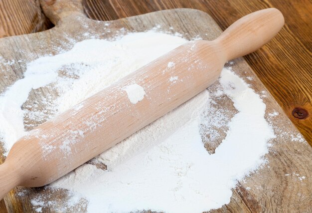 Un rodillo de madera y una tabla de cortar espolvoreados con harina mientras se hornea pan