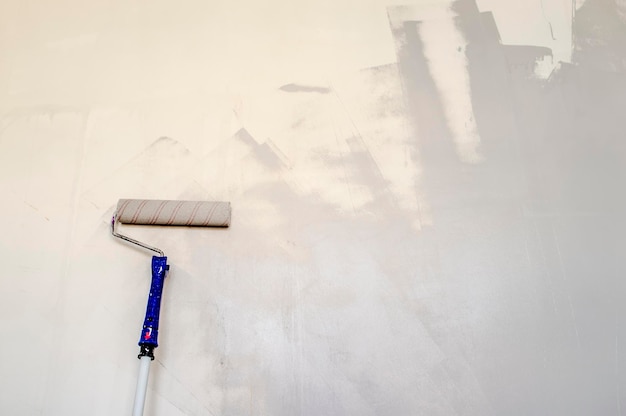 Rodillo para pintar ubicado en la pared y listo para reparar en la habitación