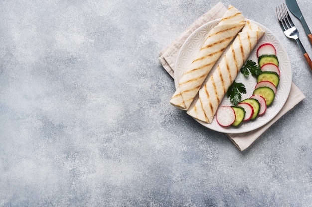 Foto rodillo con queso y hierbas. pan pita a la plancha con relleno. ensalada de rábano y pepino. el concepto de un desayuno saludable. copia espacio