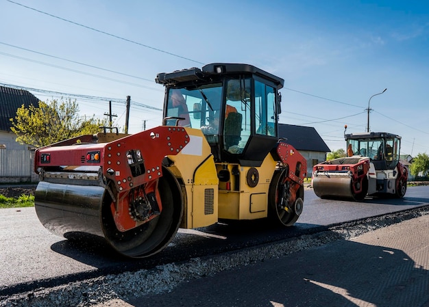 Foto rodillo de vibraciones pesadas en el pavimento asfáltico trabajando en el nuevo sitio de construcción de carreteras