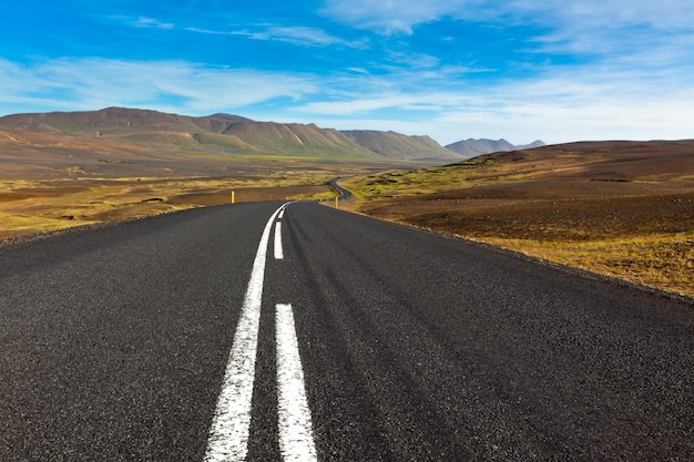 Rodovia através da paisagem do campo de lava de cascalho sob um céu azul de verão