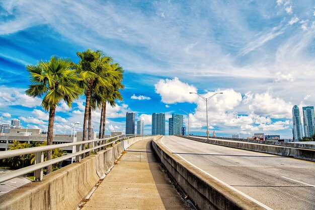 Rodovia de Miami ou via pública para veículos de transporte e arranha-céus urbanos no fundo do céu azul nublado próximo ao porto, Miami Dade