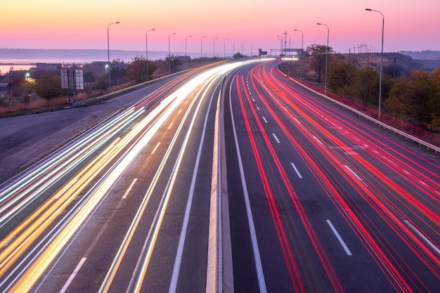 Rodovia suburbana à noite após o pôr do sol. Vestígios de faróis e lanternas traseiras de tráfego intenso