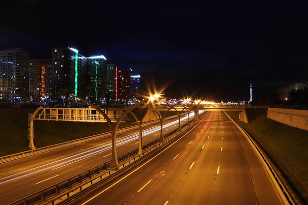 Rodovia urbana noturna com trilhas leves de carros