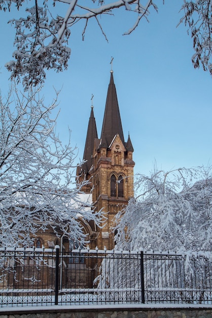 Römisch-katholische Kirche mit Eisenzaun auf blauem Himmelshintergrund im Winter