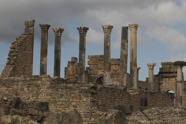 Römische Ruinen von Volubilis in Marokko – Die am besten erhaltenen römischen Ruinen liegen zwischen den Kaiserstädten Fès und Meknès auf einer fruchtbaren Ebene, umgeben von Weizenfeldern.