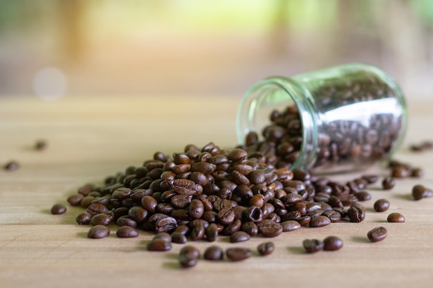 Röstkaffeebohnen in den Glasflaschen gesetzt auf den Tisch mit Naturhintergrund.