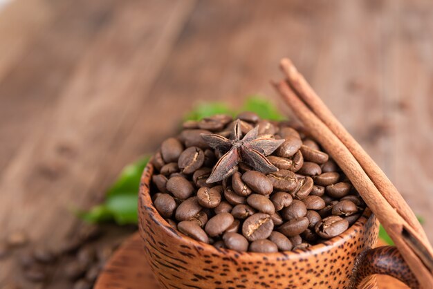 Röstkaffeebohnen in der hölzernen Schüssel mit Zimtstange und Sternanis