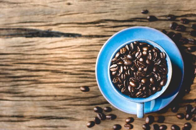 Röstkaffeebohnen setzten sich in eine blaue Kaffeetasse.