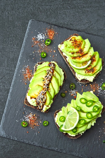 Roggen-Avocado-Toast mit Chili und Limette auf einem Stein-Servierbrett. Gesunder Avocado-Toast. Draufsicht. Flach liegen.