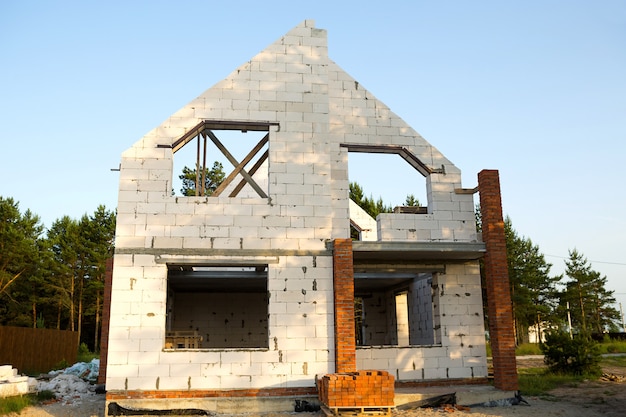 Rohbauobjekt ist ein zukünftiges Haus aus einem Porenbetonblock. 1. Stock mit Dachboden. Wohnen in ländlichen Gebieten ist im Bau. Wände mit Fenstern