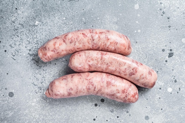 Rohe Bratwürste zum Grillen mit Gewürzen Grauer Hintergrund Ansicht von oben Kopieren Sie Platz