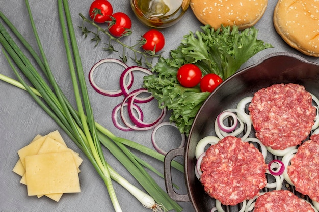 Rohe Burger mit Zwiebeln in einer Bratpfanne