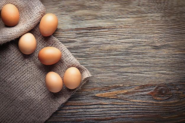 Rohe Eier auf Sackleinen auf Holztisch