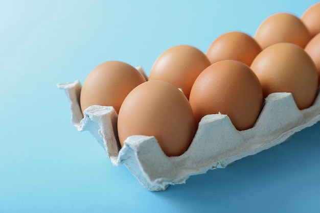 Rohe Eier im Paket auf blauem Hintergrund