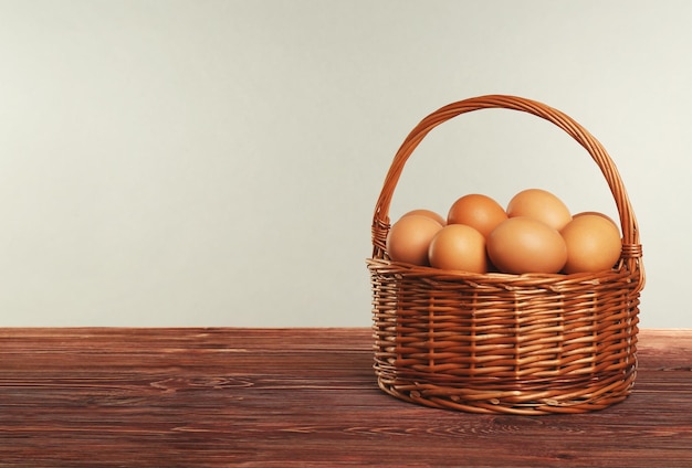 Rohe Eier im Weidenkorb auf Holztisch