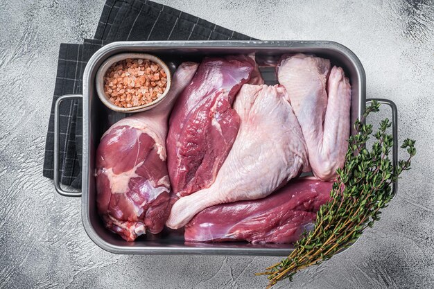 Rohe Ente Teile frische Brust Filet Beine Flügel in einem Küchentablett Weißer Hintergrund Ansicht von oben