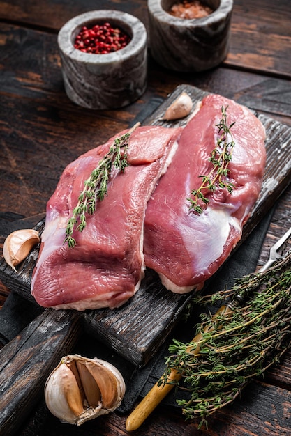 Rohe Entenbrust, Geflügelfleischsteaks auf Holzbrett zum Kochen bereit. Hölzerner Hintergrund. Ansicht von oben.