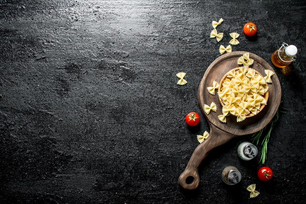 Rohe Farfalle-Nudeln in einer Schüssel mit Rosmarintomaten, Gewürzen und Öl