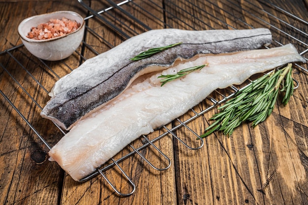 Rohe Fischfilets vom Grill mit Rosmarin und Kräutern. Hölzerner Hintergrund. Ansicht von oben.