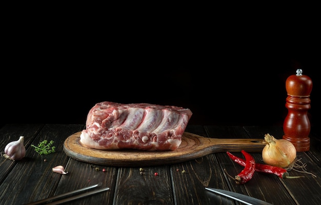 Rohe Fleischrippen auf einem Küchenschneidebrett, bevor Sie ein Abendessen mit Gewürzen und Paprika zubereiten Schwarzer Platz für Menü oder Rezept