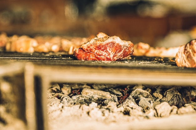 Rohe Fleischstücke, die langsam im Grill eines Restaurants kochen.