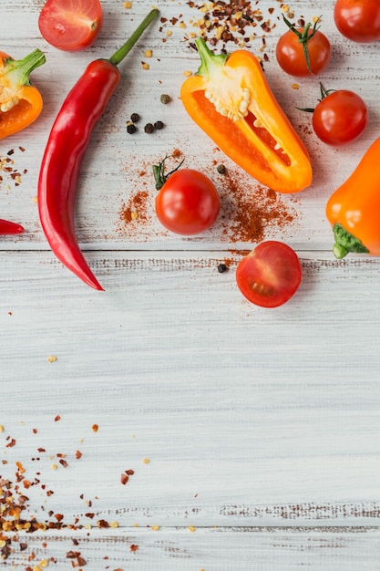 Rohe frische Bio-Mischung bunte Paprika, Kirschtomaten und verschiedene Gewürze auf weißem Holztisch