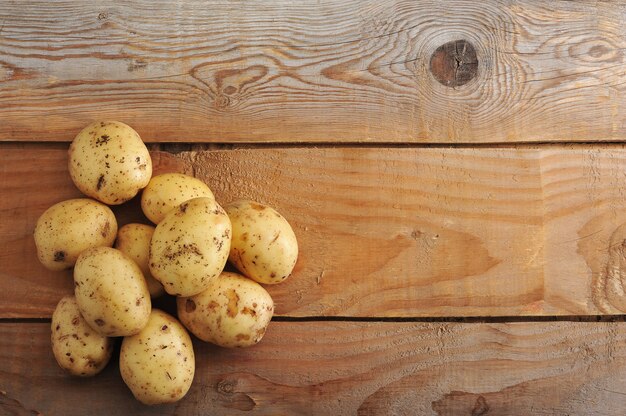 Rohe Frühkartoffeln in der Haut auf rustikaler Holzoberfläche