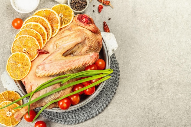 Rohe Gans mit Gemüse und Gewürzen. Traditionelle Zutat für die Zubereitung festlicher und gesunder Speisen im rustikalen Stil. Heller konkreter Steinhintergrund, Draufsicht