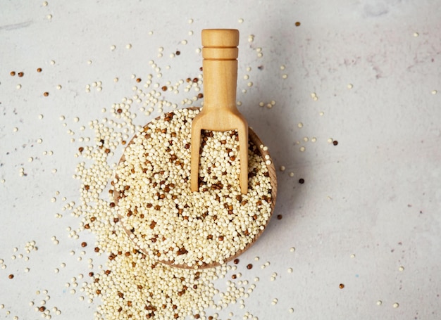 Rohe gemischte Quinoa in Schüssel und Schaufel auf hellem Betonhintergrund. Gesundes und diätisches Superfood