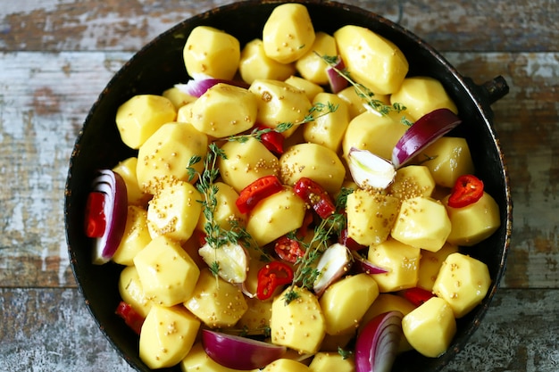 Rohe geschälte Kartoffeln ganz in einer Pfanne mit Gewürzen, Kräutern und Knoblauch vor dem Backen. Ofenkartoffeln kochen. Selektiver Fokus.