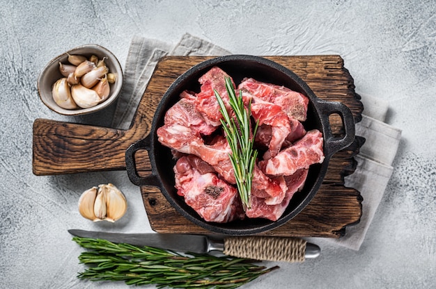 Rohe gewürfelte Fleischwürfel mit Knochen in einer Pfanne. weißer Tisch. Draufsicht.