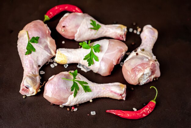 rohe Hähnchenschenkel mit Gewürzen auf einem Steinhintergrund