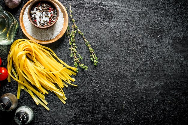 Foto rohe hausgemachte nudeln mit gewürzen, öl und tomaten